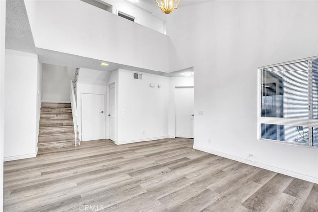 15696 Paine St, Fontana, CA 92336 - unfurnished living room with light wood-style flooring, stairway, a high ceiling, a chandelier, and baseboards