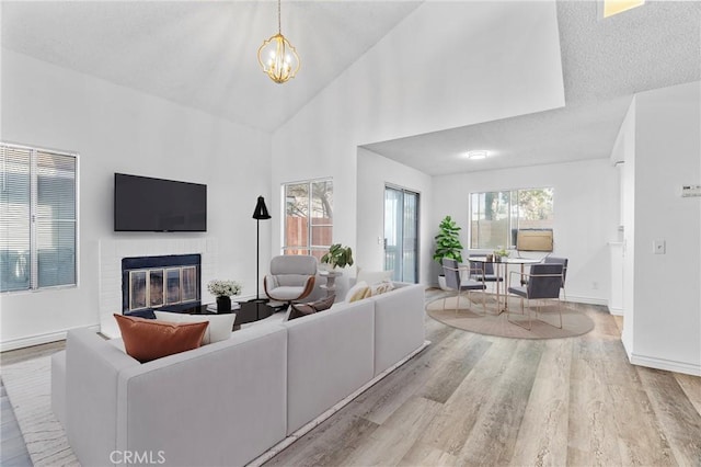 15696 Paine St, Fontana, CA 92336 - living area with wood finished floors, a fireplace, high vaulted ceiling, a chandelier, and baseboards
