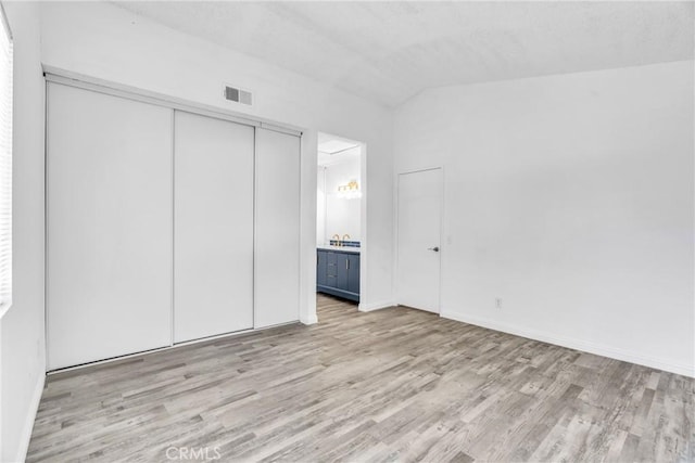 15696 Paine St, Fontana, CA 92336 - unfurnished bedroom featuring vaulted ceiling, light wood finished floors, connected bathroom, a closet, and a sink