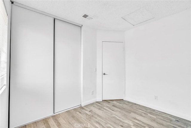 15696 Paine St, Fontana, CA 92336 - unfurnished bedroom with light wood-style flooring, a textured ceiling, a closet, baseboards, and attic access