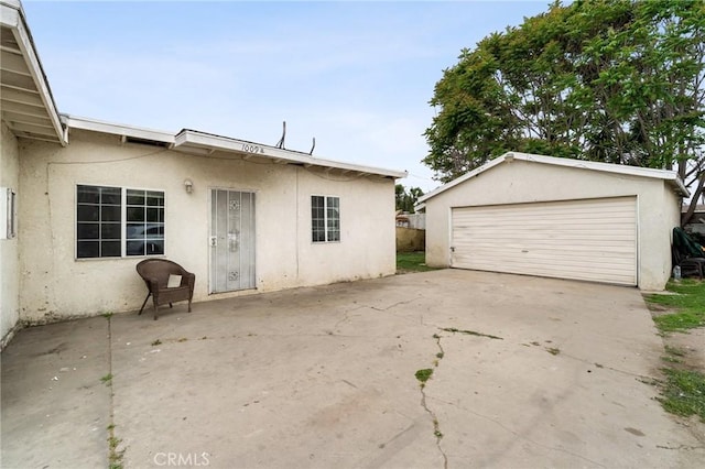 1009 E Peck St, Compton, CA 90221 - rear view of house with stucco siding, an outdoor structure, and a garage