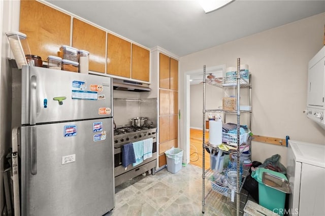 1009 E Peck St, Compton, CA 90221 - kitchen with appliances with stainless steel finishes, stacked washer / dryer, under cabinet range hood, and brown cabinetry