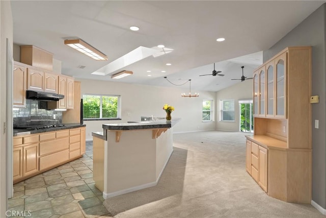 43 Edgewater Ct, Chico, CA 95928 - kitchen with light brown cabinetry, under cabinet range hood, plenty of natural light, a breakfast bar, and vaulted ceiling