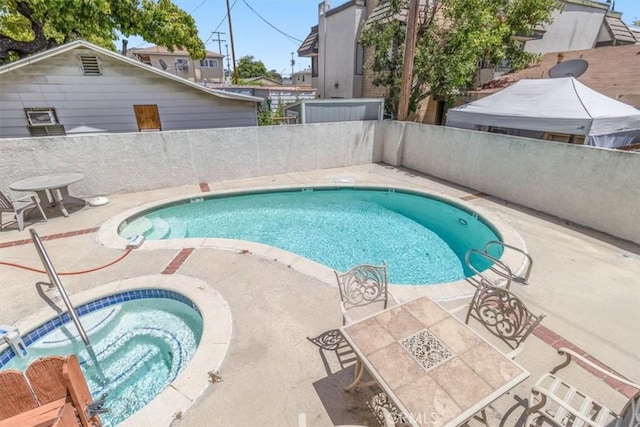 view of pool with a community hot tub, a patio area, and a fenced backyard