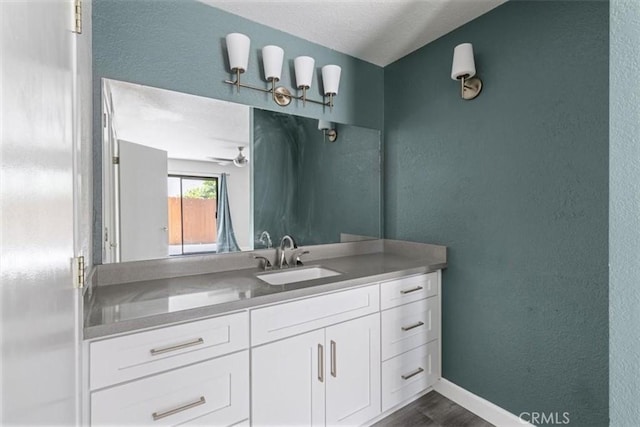 bathroom featuring vanity, wood finished floors, a textured wall, and ceiling fan