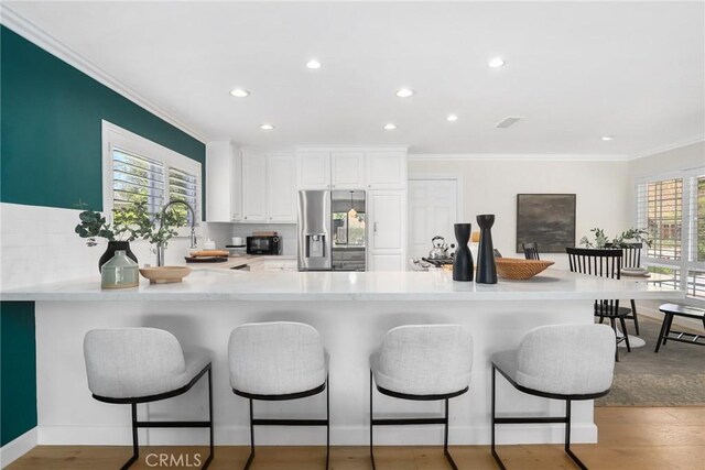 5839 Parkmor Rd, Calabasas, CA 91302 - kitchen featuring stainless steel refrigerator with ice dispenser, crown molding, light countertops, a breakfast bar area, and a peninsula