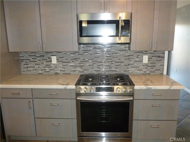26223 Crestone Dr, Menifee, CA 92586 - kitchen featuring appliances with stainless steel finishes, gray cabinets, tasteful backsplash, and light stone countertops