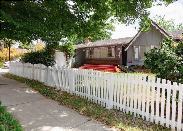 8554 Owensmouth Ave, Canoga Park, CA 91304 - view of front facade featuring board and batten siding, a chimney, a fenced front yard, and brick siding