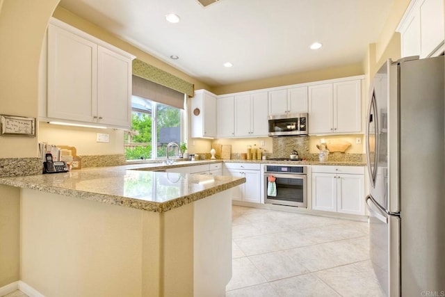 11590 Trailbrook Ln, San Diego, CA 92128 - kitchen with stainless steel appliances, a peninsula, light stone countertops, recessed lighting, and light tile patterned flooring