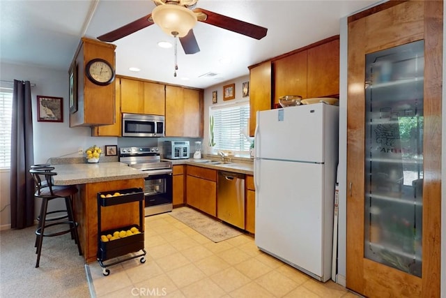 1401 Norton St, Oroville, CA 95966 - kitchen with stainless steel appliances, brown cabinetry, a peninsula, and ceiling fan