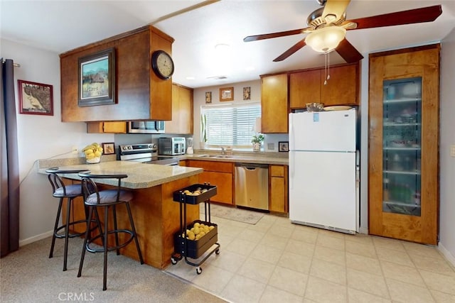 1401 Norton St, Oroville, CA 95966 - kitchen with stainless steel appliances, brown cabinetry, a peninsula, and a ceiling fan