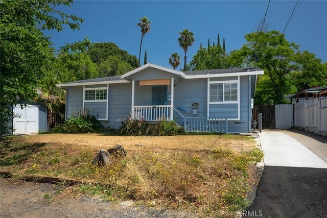 1401 Norton St, Oroville, CA 95966 - view of front of house with covered porch, a storage unit, an outbuilding, concrete driveway, and fence