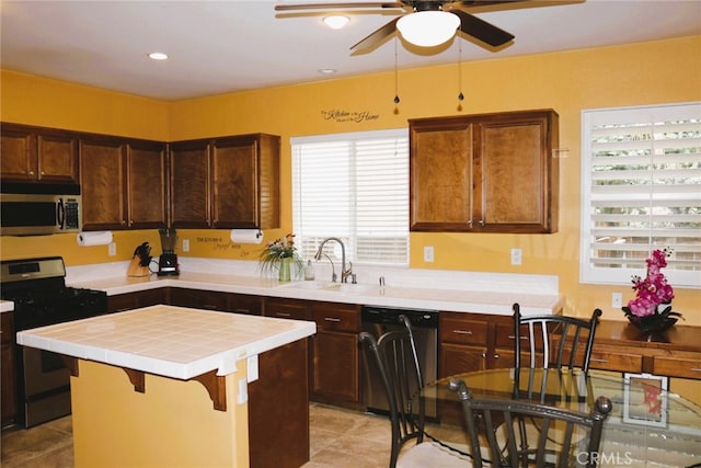 13217 Acacia Ave, Moreno Valley, CA 92553 - kitchen with stainless steel appliances, tile countertops, a sink, ceiling fan, and a kitchen island