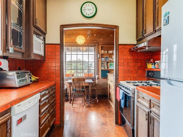6570 Moonstone Beach Dr, Cambria, CA 93428 - kitchen with white appliances, tile countertops, under cabinet range hood, glass insert cabinets, and backsplash