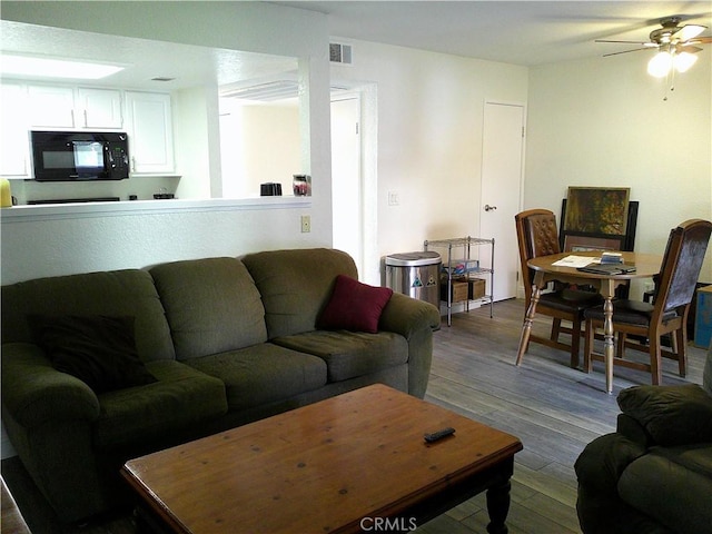 living area featuring dark wood-type flooring and a ceiling fan