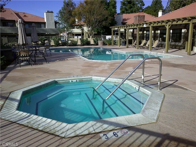 community pool with a hot tub, a pergola, and a patio area