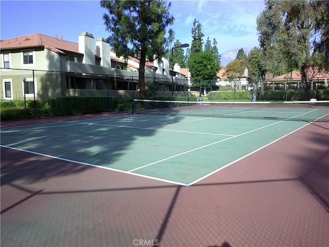 view of tennis court featuring fence, community basketball court, and a mountain view