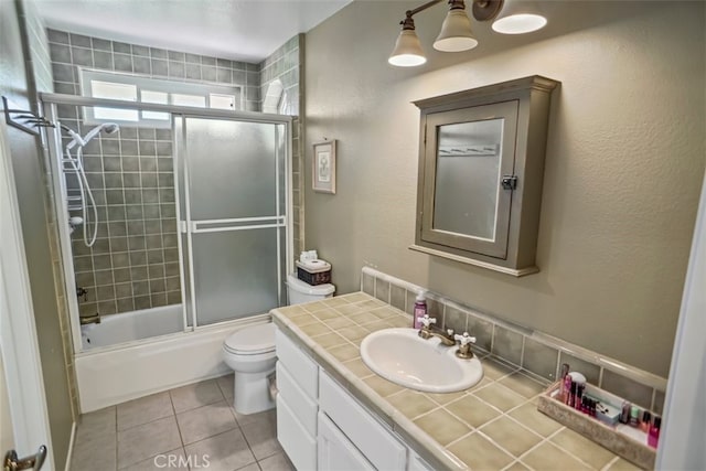 full bathroom with tile patterned floors, combined bath / shower with glass door, vanity, and toilet