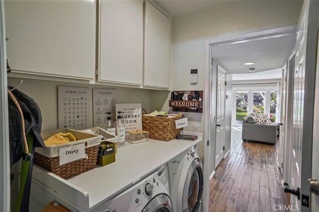 washroom with cabinet space, washer and clothes dryer, and wood-type flooring