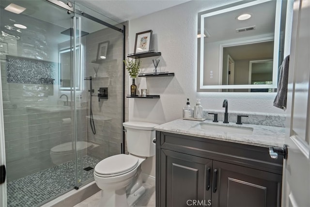 bathroom featuring toilet, a textured wall, vanity, and a stall shower