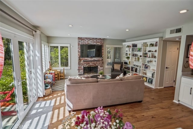 living room featuring a brick fireplace, light wood-style flooring, and recessed lighting
