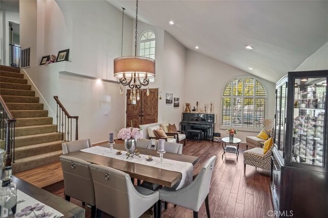 dining area with stairs, high vaulted ceiling, recessed lighting, dark wood-type flooring, and a chandelier