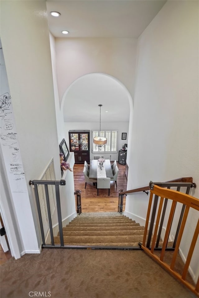 stairs with arched walkways, baseboards, recessed lighting, and carpet floors