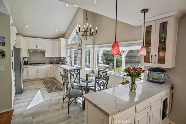kitchen featuring stovetop, freestanding refrigerator, white cabinets, a peninsula, and light stone countertops