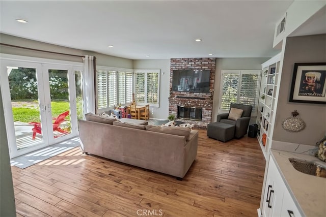living room featuring plenty of natural light, light wood finished floors, a fireplace, and recessed lighting