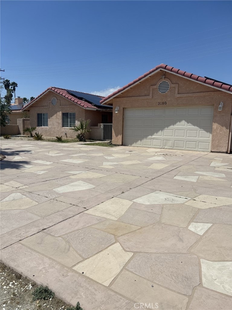 view of front of house featuring a tile roof, roof mounted solar panels, stucco siding, concrete driveway, and a garage