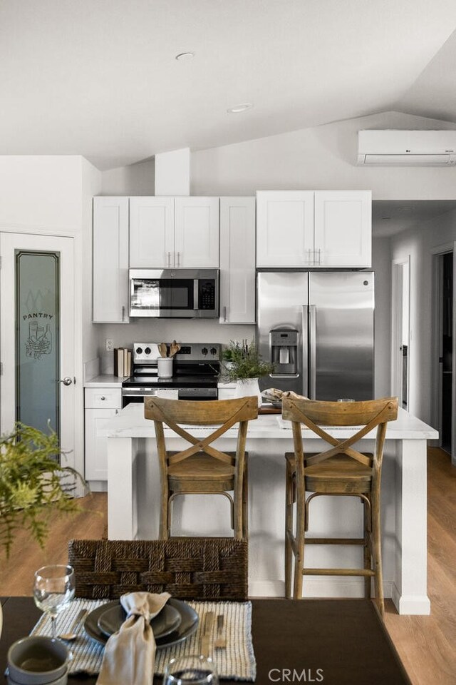 6333 Graham Rd, Paradise, CA 95969 - kitchen featuring appliances with stainless steel finishes, vaulted ceiling, an AC wall unit, and white cabinets