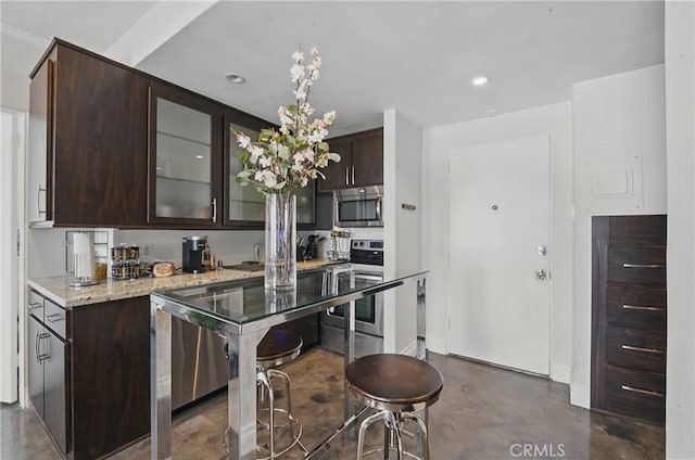 140 Linden Ave Unit 615, Long Beach, CA 90802 - kitchen featuring stainless steel appliances, concrete floors, dark brown cabinets, glass insert cabinets, and light stone counters
