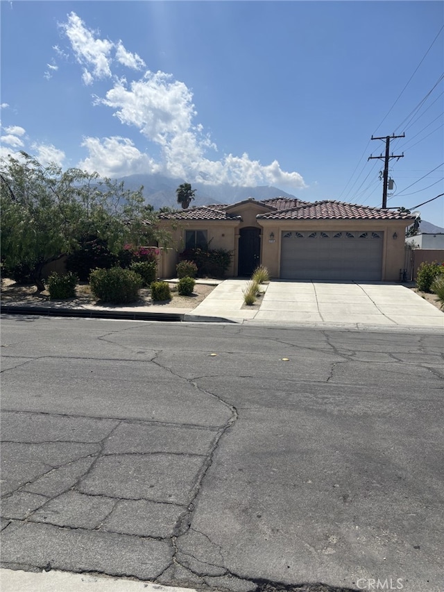 mediterranean / spanish house with an attached garage, a tiled roof, concrete driveway, and stucco siding