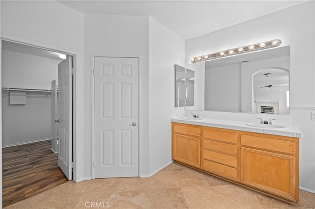 bathroom featuring a ceiling fan, double vanity, and a spacious closet