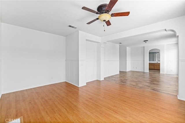 unfurnished room with a ceiling fan, light wood-style flooring, and arched walkways