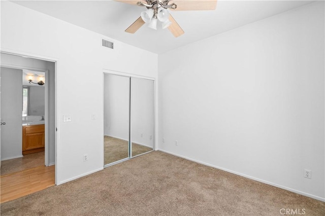 unfurnished bedroom featuring light colored carpet, a closet, baseboards, and a ceiling fan
