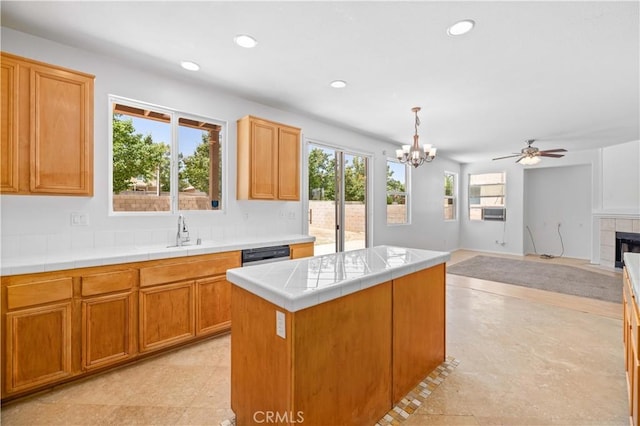 kitchen featuring a sink, a chandelier, a tile fireplace, recessed lighting, and a ceiling fan