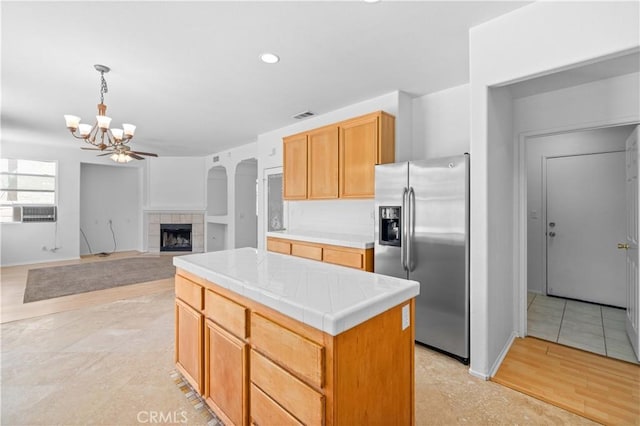 kitchen with stainless steel refrigerator with ice dispenser, a chandelier, tile countertops, baseboards, and a tiled fireplace