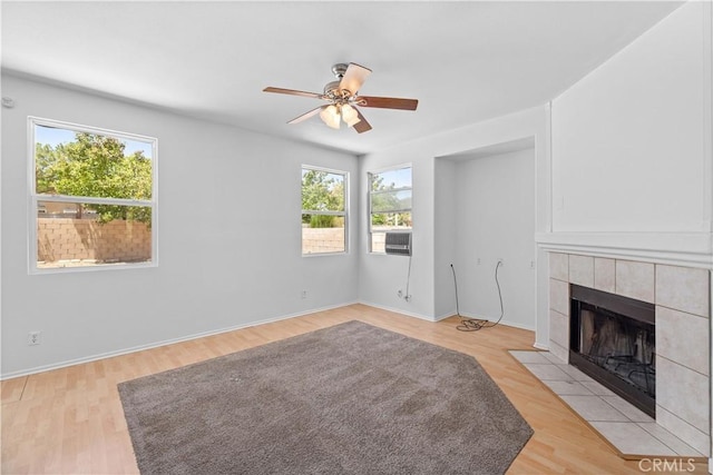 unfurnished living room featuring a ceiling fan, a fireplace, light wood-type flooring, and baseboards