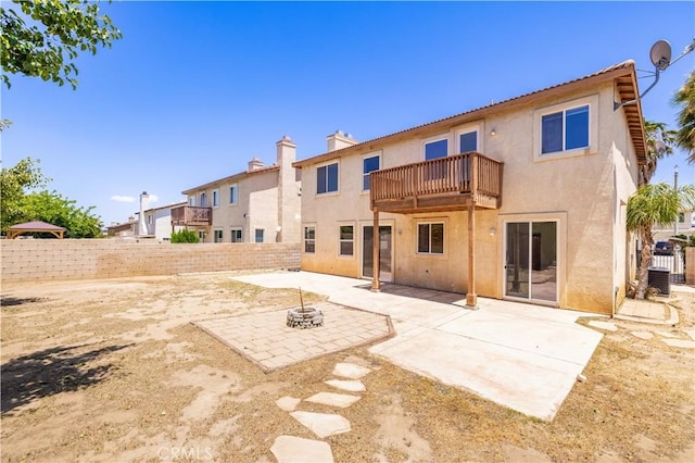 rear view of property with a balcony, stucco siding, a fenced backyard, and a patio area