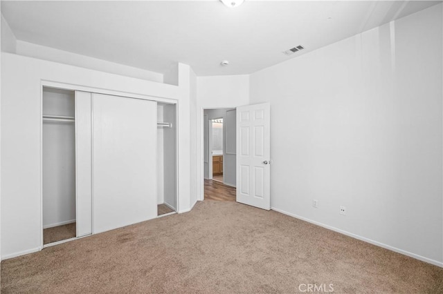 unfurnished bedroom with carpet, a closet, and baseboards