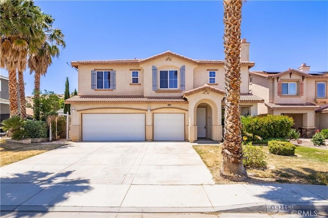 mediterranean / spanish house with stucco siding, a garage, concrete driveway, and a tiled roof