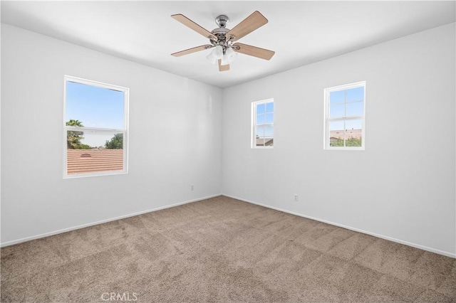 carpeted empty room featuring baseboards and a ceiling fan