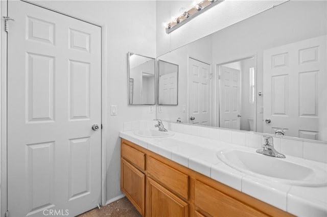 bathroom with double vanity and baseboards