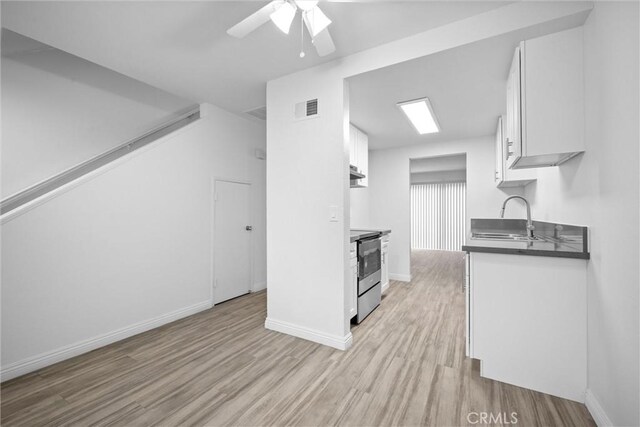 2709 S Baker St, Santa Ana, CA 92707 - kitchen with stainless steel electric stove, a sink, white cabinets, light wood-style floors, and a ceiling fan