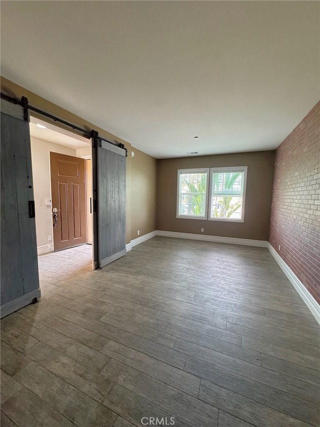 3397 Sequoia Ct, Perris, CA 92570 - unfurnished room with a barn door, dark wood-style floors, baseboards, and brick wall