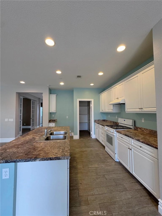 3397 Sequoia Ct, Perris, CA 92570 - kitchen featuring gas range gas stove, a sink, under cabinet range hood, baseboards, and white cabinetry