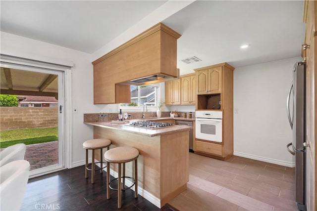 6028 Hart Ave, Temple City, CA 91780 - kitchen featuring stainless steel appliances, a kitchen breakfast bar, light brown cabinets, a peninsula, and baseboards
