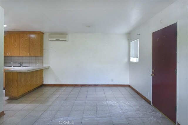 5625 Matilija Ave, Valley Glen, CA 91401 - unfurnished dining area featuring a wall unit AC, baseboards, a sink, and light tile patterned flooring