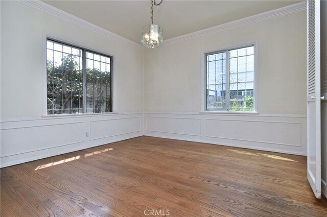 5625 Matilija Ave, Valley Glen, CA 91401 - spare room featuring crown molding, a chandelier, plenty of natural light, wood finished floors, and a wainscoted wall
